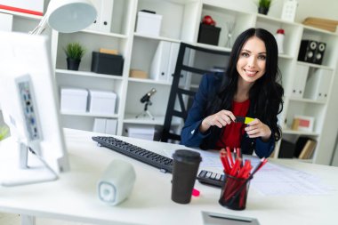 Güzel bir genç kız ofiste masada oturur ve sarı bir işaret onun elinde tutan.