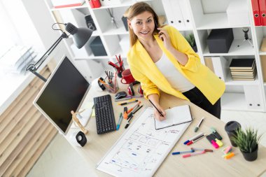 Genç bir kız bir masanın ayakta, telefonda konuşurken, onun elinde bir kalem tutan ve notları bir defterde yapma. Önce kız masanın üzerinde bir manyetik tahta