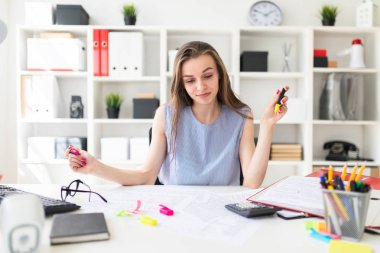 Güzel genç kız ofiste bir masada oturur ve eller sarı ve pembe işaretleyicilerini tutar.