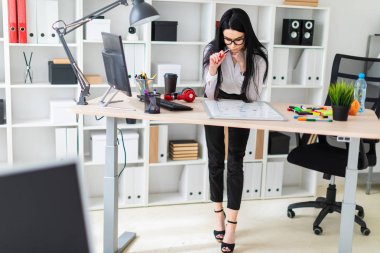 Genç bir kız bir bilgisayar masası duruyor ve bir işaretleyici manyetik bir tahtaya çizer.