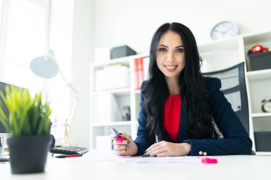Güzel genç kız masa ofis belgeleri ile çalışıyor. Kız belgedeki önemli noktaları pembe bir marker ile vurgulamaktadır..