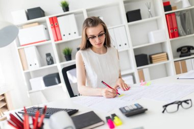 Güzel genç kız ofiste masada oturmuş, elinde kalem tutan ve belgeleri doldurma.