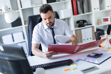Bir adam ofiste masada oturan ve belgeleriyle çalışma.