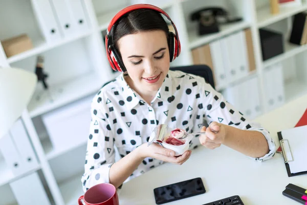Kulaklık Office kırmızı dolgulu yoğurt yemek masasında oturan güzel genç kız. — Stok fotoğraf