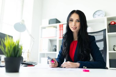 Güzel genç kız masa ofis belgeleri ile çalışıyor. Kız belgedeki önemli noktaları pembe bir marker ile vurgulamaktadır..