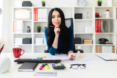 Genç bir kız masada ofiste oturur, onun elinde bir kalem tutan ve belgeleri doldurur.