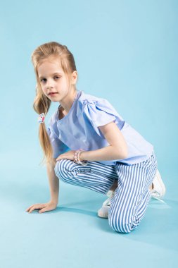 Mavi elbiseleri bir kız mavi bir arka plan üzerinde oturuyor.