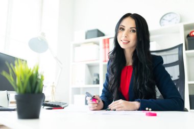 Güzel genç kız masa ofis belgeleri ile çalışıyor. Kız belgedeki önemli noktaları pembe bir marker ile vurgulamaktadır..