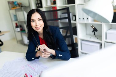 Güzel genç kız belgesiyle, office masada oturan arıyor.