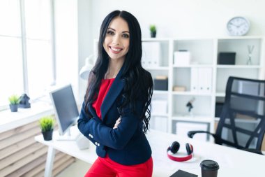 İş takım elbiseli güzel genç kız ofiste, bir masaya eğilmiş duruyor.