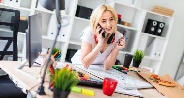 Genç bir kız bir masanın ayakta, telefonda konuşurken ve bir işaretleyici elinde tutan. Masaya manyetik bir pansiyondur. Kızlar kulaklık boynuna asmak.