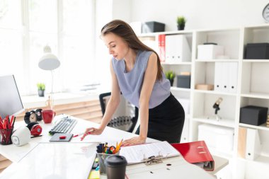 Güzel genç kız bir ofiste yakınındaki bir tablo duruyor ve bir işaretleyici manyetik bir tahtaya çizer.