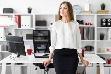 Genç bir kız ofiste bir tabloda yaslanmış ve gözlük onun elinde tutan duruyor.