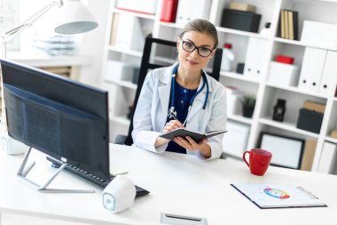 Beyaz bir elbise içinde genç bir kız ofiste bir masada oturur ve bir kalem ve defter elinde tutar. Bir stetoskop boynunda asılı.