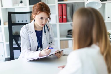 Beyaz bir elbise içinde güzel bir genç kız ofiste masada oturan ve muhatap ile iletişim. Kız notlar sayfasında yapar..