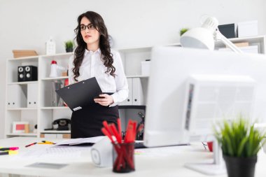 Güzel bir genç kız bir ofis masası standları ve notlar için bir sayfası tutar.