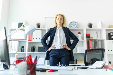 Genç bir kız ofiste, bir tabloda yakınındaki ellerinin onu kalça üzerinde bekleyen.