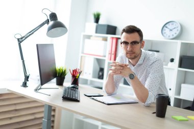 Ofiste bir tabloda yakınındaki bir genç adam gözlük standları.