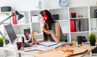 Genç bir kız bir tablo bir yeşil işareti ve bir parça pizza elinde tutan duruyor. Önce kız masanın üzerinde manyetik bir pansiyondur. Kulaklıklar giyen kız kafasına.