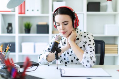 Kulaklık ve mikrofon ofis masada oturan ve konuşmak güzel genç kız.