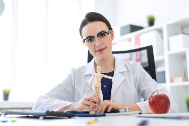 Beyaz bir elbise içinde güzel bir genç kız bir masada oturan ve bir adam ahşap bir rakam onun elinde tutan.