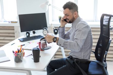 Hafif bir gömlek ve karanlık pantolon sakallı bir adam ofiste çalışıyor. alan derinliği ile fotoğraf.