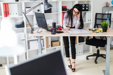 Genç bir kız bir bilgisayar masası duruyor ve bir işaretleyici manyetik bir tahtaya çizer.