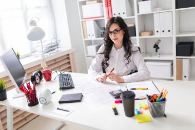 Genç bir kız ofis masada oturur ve onun sol elinde kalem tutan.