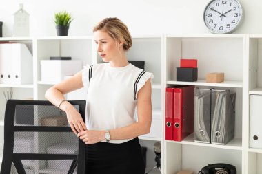 Genç sarışın kız yanındaki belgelerle, raf ofiste ellerini Koltuğun arkasında bekleyen.