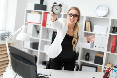 Genç bir kız ofiste bir tabloda yakınındaki anlamına gelir ve bir çalar saat tutar.