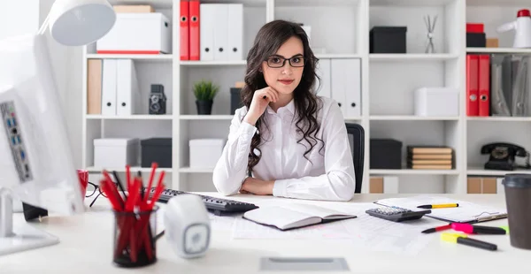 Hermosa joven está sentada a la mesa en la oficina . — Foto de Stock