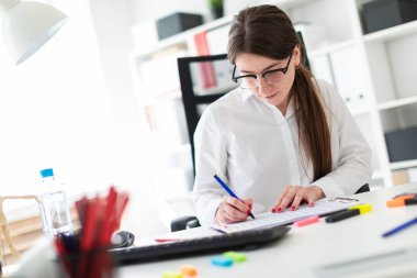 Kızıl saçlı genç kız gözlük ve beyaz bir bluz büyüleyici parlak bir ofiste çalışıyor. alan derinliği ile fotoğraf.
