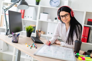 Genç bir kız kulaklık tablo anlamına gelir ve bir işaretleyici manyetik bir tahtaya çizer.