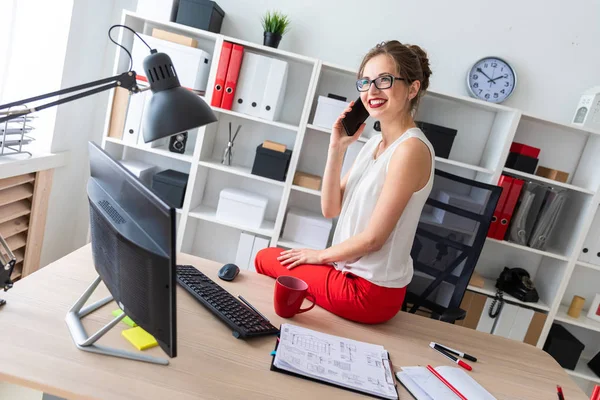 Uma jovem sentou-se na mesa do escritório e estava falando ao telefone . — Fotografia de Stock