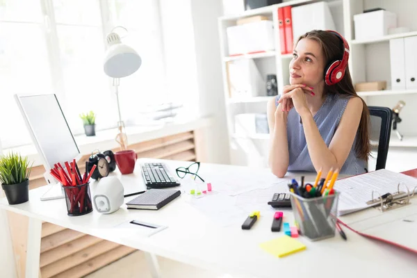 Belle jeune fille dans le bureau s'assoit à une table en casque rouge . — Photo