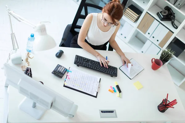 Hermosa joven en la oficina trabajando con documentos, calculadora, bloc de notas y computadora . — Foto de Stock