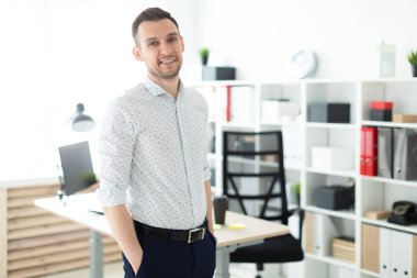 Genç adam sahanın ofiste bir tabloda, elleri cebinde yakınındaki.