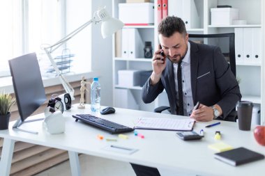 Sakallı bir adam bir takım elbise ile parlak bir ofiste çalışıyor. alan derinliği ile fotoğraf.