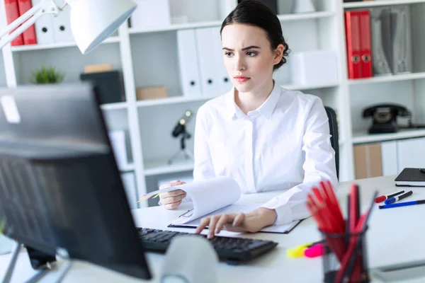 Jong meisje in het kantoor werken met documenten op de computer. — Stockfoto