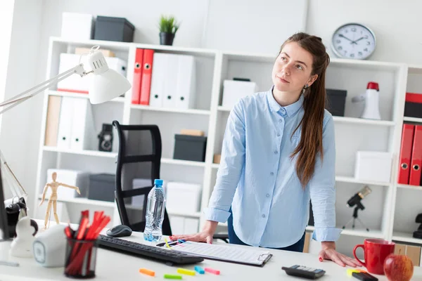 En ung flicka på kontoret står nära bordet och sätta händerna på den. — Stockfoto