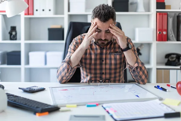 Bir adam ofiste bir masada oturuyor ve manyetik bir gemide grafik görünüyor.