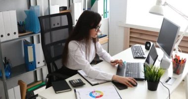 belgeleri doldurma ve modern ofis içinde laptop üzerinde çalışan iş kadını