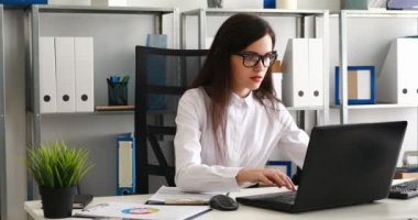 gözlükleri çıkar alarak ve kameraya bakarak işkadını üstünde laptop modern ofis çalışma