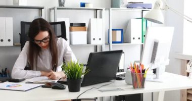 belgeleri doldurma ve modern ofis içinde laptop üzerinde çalışan iş kadını