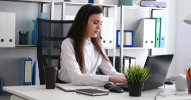 kulaklıktaki konuşma ve modern ofiste dizüstü kullanan kadın