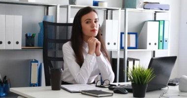 kafa elinde yaslanır, kulaklık düzleme ve kameraya bakarak kadın