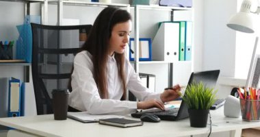 kulaklıktaki konuşma ve modern ofiste dizüstü kullanan kadın