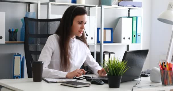 女性のヘッドセットで話すと近代的なオフィスにラップトップを使用して — ストック動画