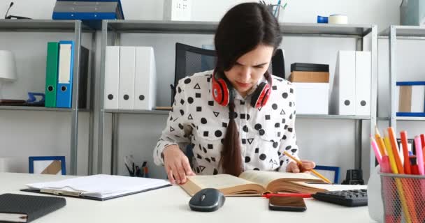 Žena Červeným Sluchátka Bedrech Thumbing Knihu Psaní Tužkou Papír — Stock video