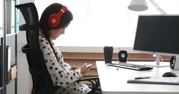Επιχειρηματίας Στα Κόκκινα Ακουστικά Χρησιμοποιώντας Smartphone Στο Σύγχρονο Γραφείο — Αρχείο Βίντεο